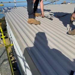 Installing SureClad corrugated roofing during a re-roofing project in Fairhaven.
